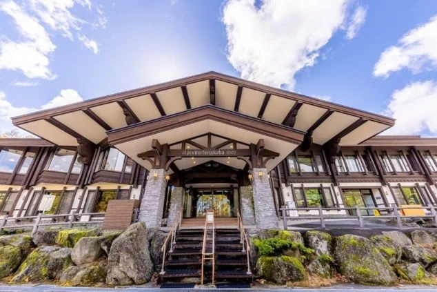 「Alpendorf Shirakaba 1992」と書かれた看板がある、アルプス風ホテルの外観が映る職場のイメージ画像。