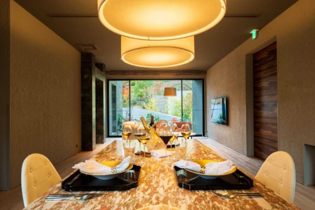 円形の大きな照明が印象的な高級感あふれる個室ダイニング。大理石のテーブルにはワイングラスや食器が美しくセットされている。