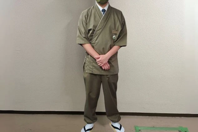 オリーブグリーンの作務衣風の上着にパンツを着用し、白足袋と草履を履いた接客全般スタッフの制服の画像。