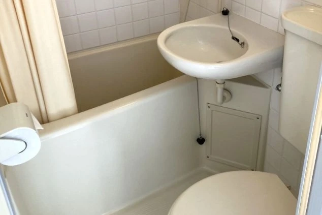 リゾートバイトの個室寮にあるユニットバス。浴槽、洗面台、トイレが一体となった、清潔でプライベートな設備の画像。