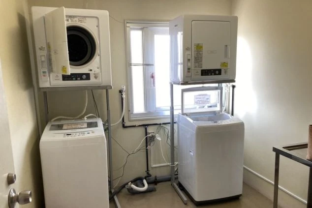 リゾートバイト寮のランドリースペース。洗濯機と乾燥機が複数台設置されており、共同で利用できる便利な設備の画像。