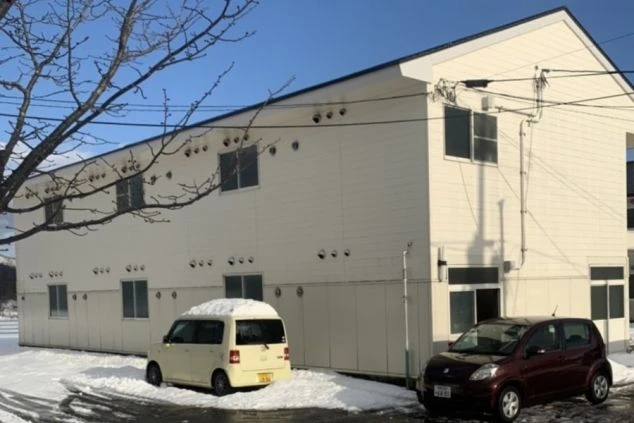 冬の雪景色に佇むリゾートバイトの寮の外観画像。