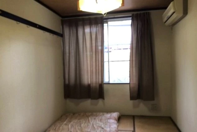 リゾートバイトの個室寮。畳敷きの部屋に布団とエアコンが備え付けられており、窓から光が差し込んでいる。