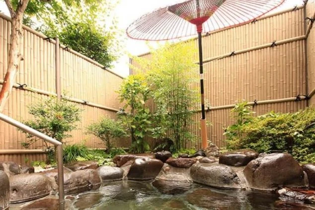 竹垣に囲まれた岩造りの露天風呂の画像。