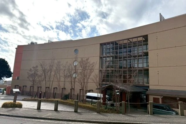 大きなガラス窓と丸窓が特徴的な、ベージュの外壁の建物。