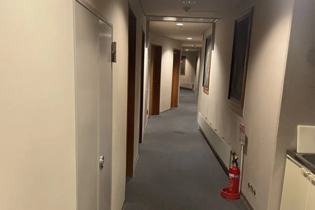 ドアが並ぶ、カーペット敷きの集合住宅または施設の共用廊下。