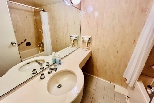 広々とした洗面台と鏡が特徴のリゾートバイトの寮の浴室。仕事の疲れを癒し、身だしなみを整えるプライベート空間。