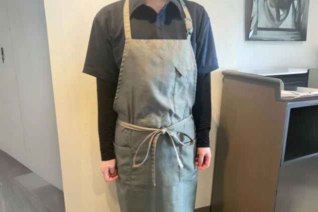 客室清掃スタッフの制服。落ち着いたグレーのエプロンスタイル。裏方業務のリゾートバイトの服装。