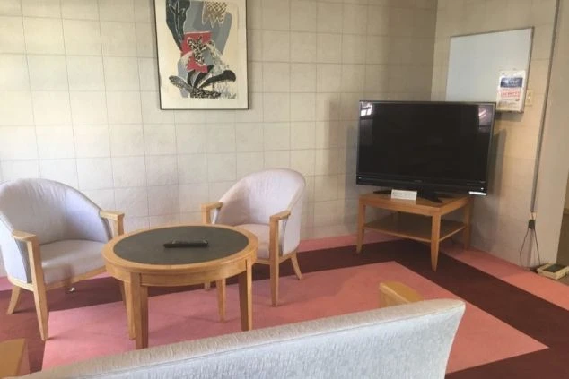 女子寮の共用スペース(談話室)の画像。ソファー、テーブル、テレビが置かれている。