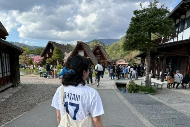 世界遺産・白川郷の集落を散策する観光客。茅葺き屋根の合掌造りの家々が並ぶ、日本の原風景が広がっています