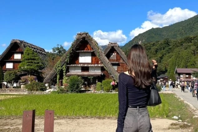 世界遺産・白川郷の集落を散策する観光客。茅葺き屋根の合掌造りの家々が並ぶ、日本の原風景が広がっています