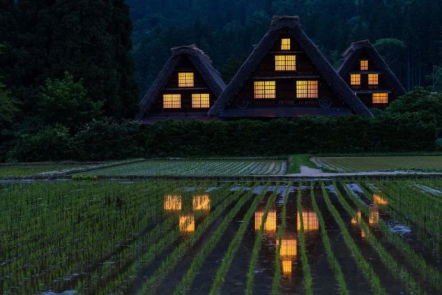 夕暮れ時の白川郷。田植えが終わった水田に、合掌造りの家々の灯りが鏡のように映り込む、幻想的な景色。リゾートバイトの休日に、写真撮影に訪れたい場所です。