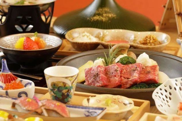 旅館で提供される豪華な会席料理。陶板で焼く霜降り和牛や、新鮮なお造り、季節のデザートなど、目でも楽しめる料理が並びます。