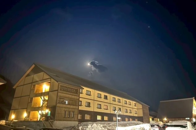 雪が積もる夜のゲレンデに佇むロッジ風リゾートホテルと月明かりの画像。