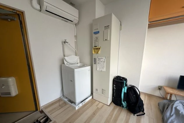 リゾートバイトの個室寮に備え付けられた洗濯機とエアコン。部屋で洗濯ができるため、非常に便利で快適に過ごせます。