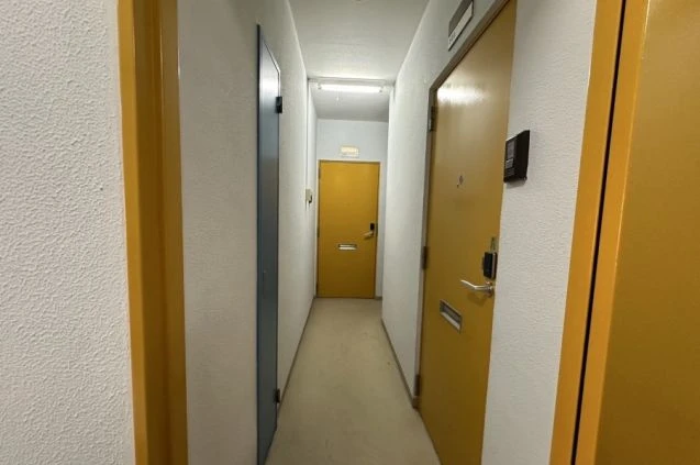 リゾートバイトの寮の清潔で明るい廊下。各個室のドアが並び、プライバシーが保たれた環境です。