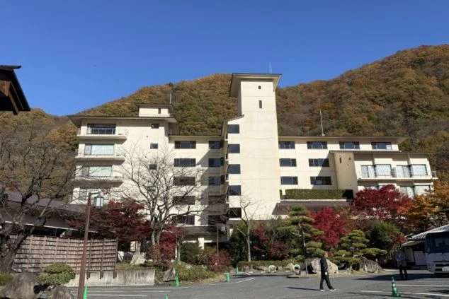 白い建物と紅葉した木々、青空が広がっています。