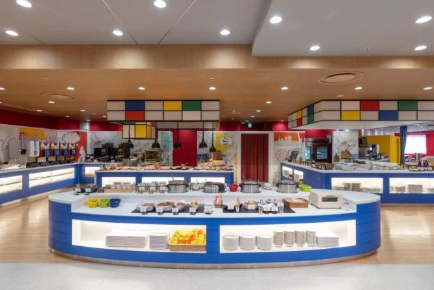 カラフルでモダンなデザインのホテルレストランのビュッフェ会場。様々な料理が並び、リゾートバイトで調理補助やレストランサービスとして働くイメージが伝わる画像。