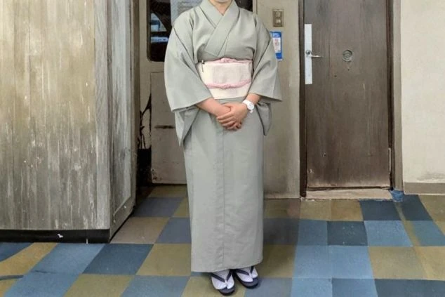 女性の仲居スタッフ用制服画像。淡いグレーの落ち着いた着物スタイル。