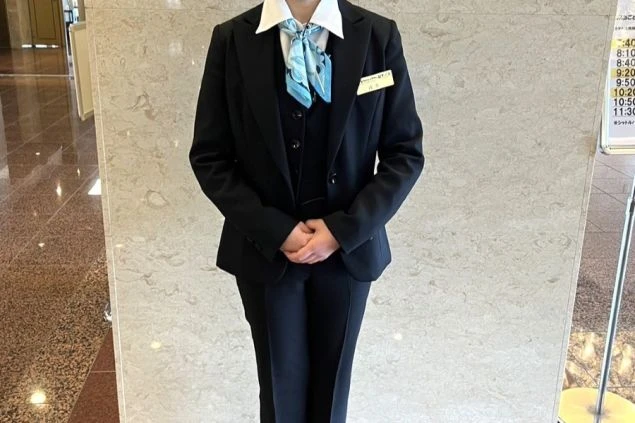 フロントで働く女性スタッフの制服。白いシャツに黒いベストとパンツを合わせた清潔感のあるスタイル。