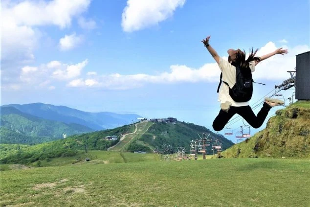 琵琶湖グランドホテルの正面外観。低層のロビー棟と、段々になったバルコニーが特徴的な高層棟。手前はアスファルトの駐車場で、奥には琵琶湖が見える。