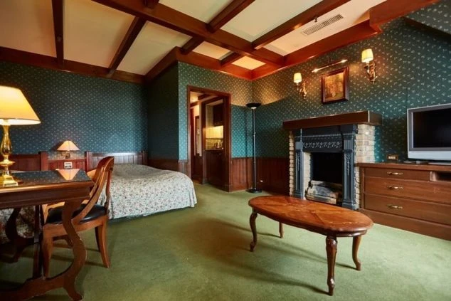 暖炉や木製の家具が置かれた、落ち着いた雰囲気の客室。ベッドやテレビ、デスクも備え付けられている。リゾートバイトで働くホテルの客室を表す画像。