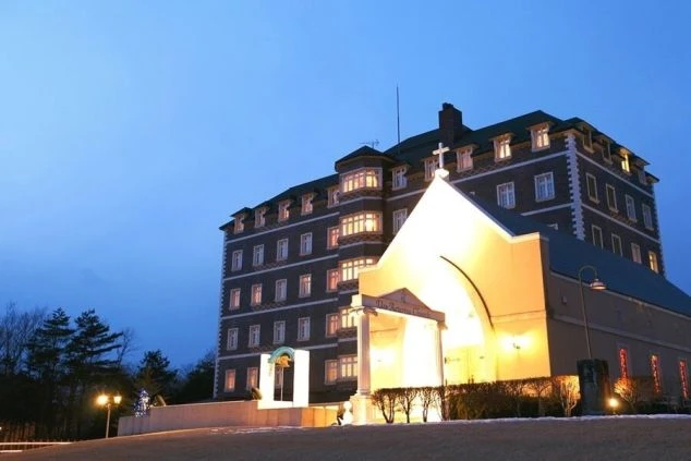 夜の空を背景に、ライトアップされた重厚なホテルが写っている画像。横にはチャペルらしき建物もあり、結婚式場や高級リゾートホテルでの仕事を表している。