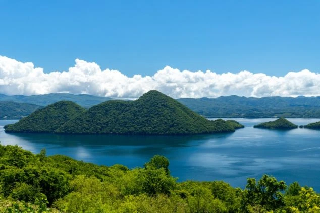 雄大な湖と山々が広がる北海道の絶景写真。語学が活かせる仕事で残業も多く、しっかり稼げるという、リゾートバイトの魅力を伝えています。