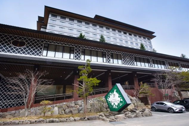 伝統的な和風の意匠（格子状の装飾）と、白い壁の近代的な高層部を組み合わせた大規模なリゾートホテルまたは温泉旅館の外観。