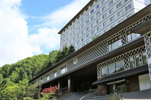 山の斜面に建てられた大規模なリゾートホテルまたは温泉旅館の建物。