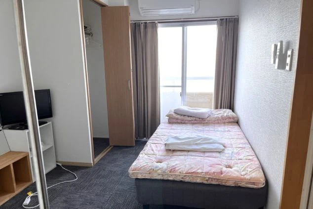  明るい窓、ベッド、木製の家具が特徴のモダンな部屋