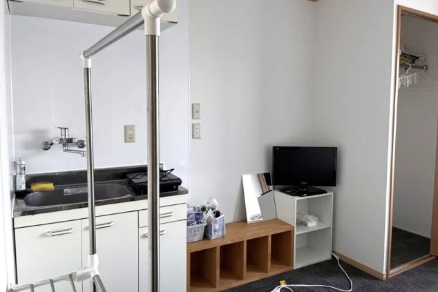 ミニ冷蔵庫、テレビ、棚が置かれたリビングスペース。