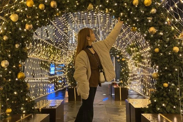 イルミネーションの中に立つ女性の画像。