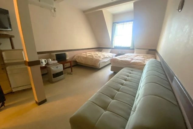 リゾートバイト寮の寝室。広々とした空間にベッドが2台、ソファ、テレビ、暖房器具などが備わっている。