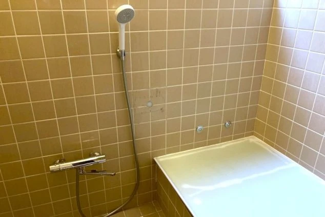 リゾートバイトの寮にあるユニットバス。浴槽とシャワーが一体になっており、ベージュのタイルで清潔感が保たれている。