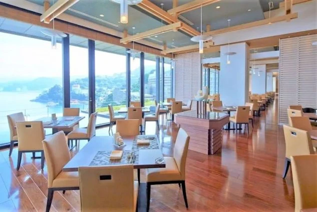 ホテルのダイニングの画像。大きな窓から海が一望でき、落ち着いた色合いのテーブルと椅子が並んでいる。リゾートバイトの仕事内容を表す、ホテルのダイニングの画像。