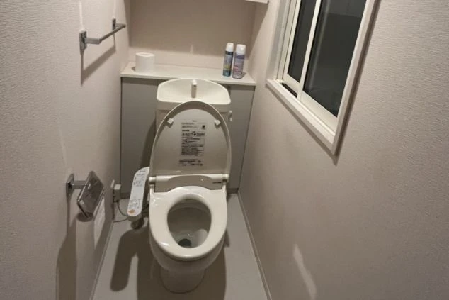 寮のトイレ。窓付きの個室に、小型の洗面台付きタンクと温水洗浄便座が設置されている。