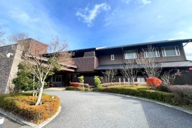 落ち着いた茶色と石造りの壁が特徴の、和風モダンな旅館またはホテルの外観。