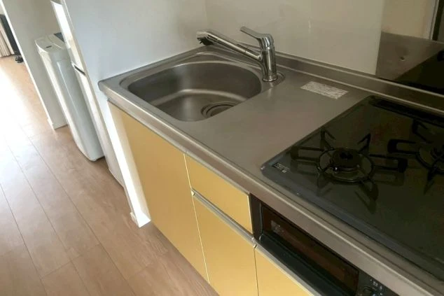 ガスコンロとシンクが設置された、イエローのキャビネットのキッチン。