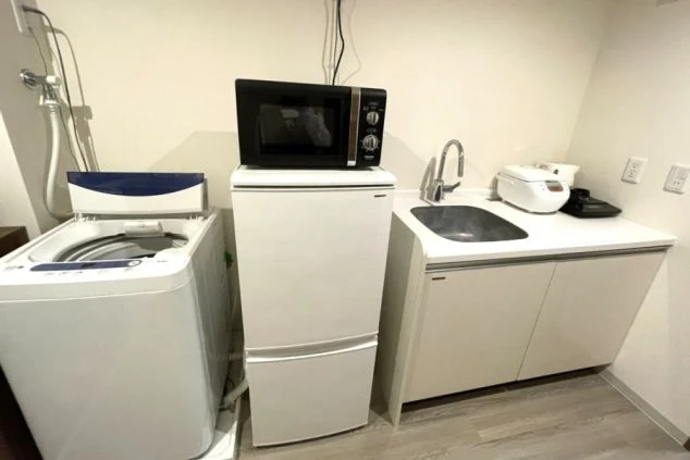 リゾートバイト寮の室内設備。洗濯機や冷蔵庫、レンジ完備のキッチンで、自室で生活が完結する便利な環境。