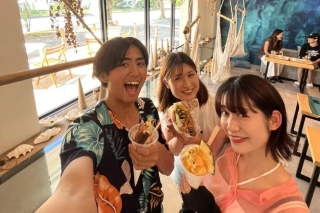 沖縄のリゾートバイトで出会った仲間と、カフェでスイーツや軽食を楽しむ様子。リゾートバイトの休日を充実させたい方や、新しい友人との出会いを求める方に魅力的なワクトリオリジナル画像。