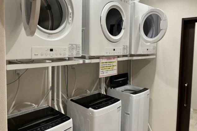リゾートバイトの社員寮にある共用ランドリーのイメージ画像。洗濯機と乾燥機が複数台設置されている。