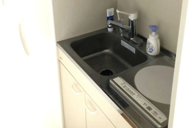 リゾートバイトの寮に完備されたキッチンの画像。自炊が可能で生活費を抑えられる(シンク、IHコンロ)。
