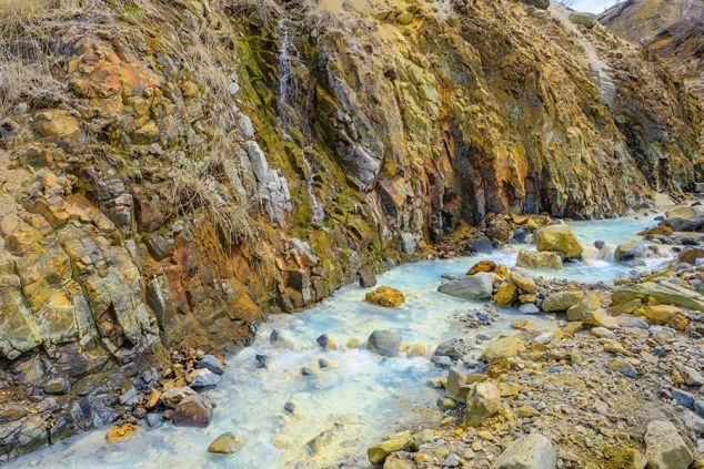 リゾートバイトの休日に観光するイメージ画像。群馬県万座温泉にある、ゴツゴツとした岩肌と白く濁った川が流れる「万座空吹」の風景。
