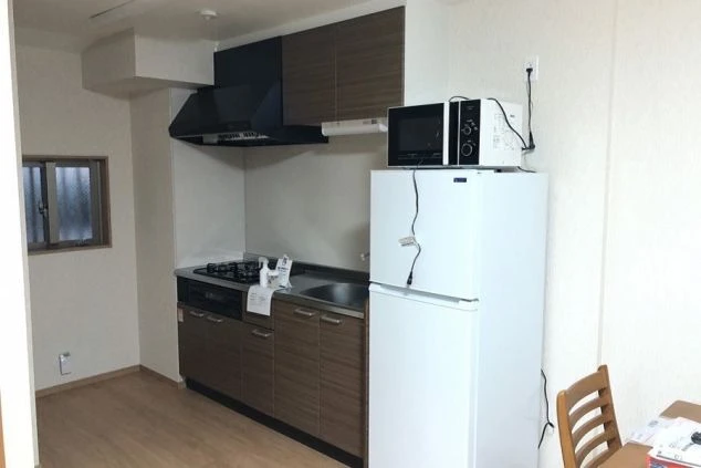 コンロ、電子レンジ、小型冷蔵庫のあるリゾートバイト寮のキッチン。
