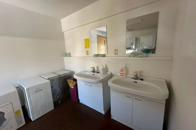 鏡と2つの洗面台が並ぶ、清潔なリゾートバイトの寮の共用洗面所の画像。