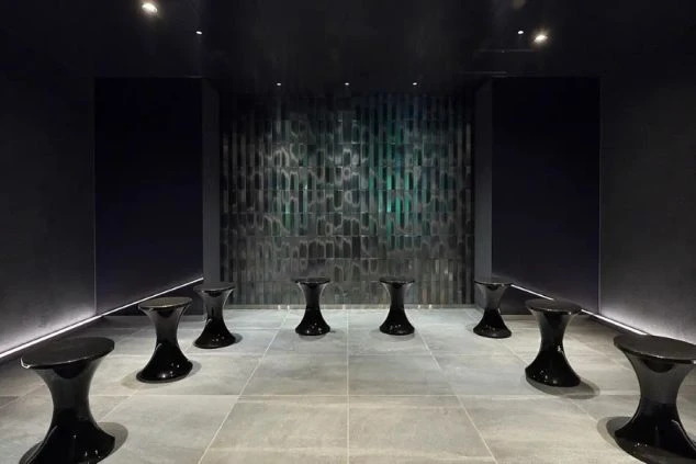 黒い壁と光る装飾、個性的なデザインの椅子が並ぶモダンな空間が映るイメージ画像。リゾートバイトの職場。