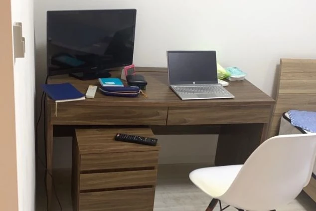 白い壁とベージュの床が柔らかい雰囲気の部屋に木製の茶色いベットフレームに白いマットレスが敷かれておりその横には木製のデスクが置いてありシンプルなデザインの部屋です