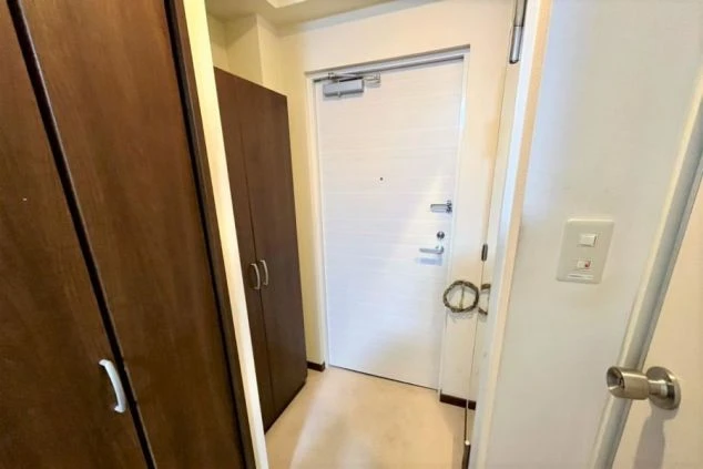 アパートの玄関周り。白い玄関のドアと木目調のシューズボックスで現代的なデザインです。