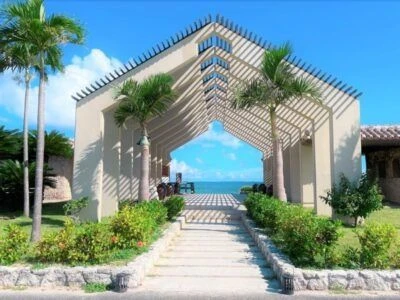 まるで結婚式場のような入り口にある、石造りのアーチ。アーチには蔦が絡まり、左右には緑の植物が植えられている。アーチの向こうには、青い海と空が広がっている。